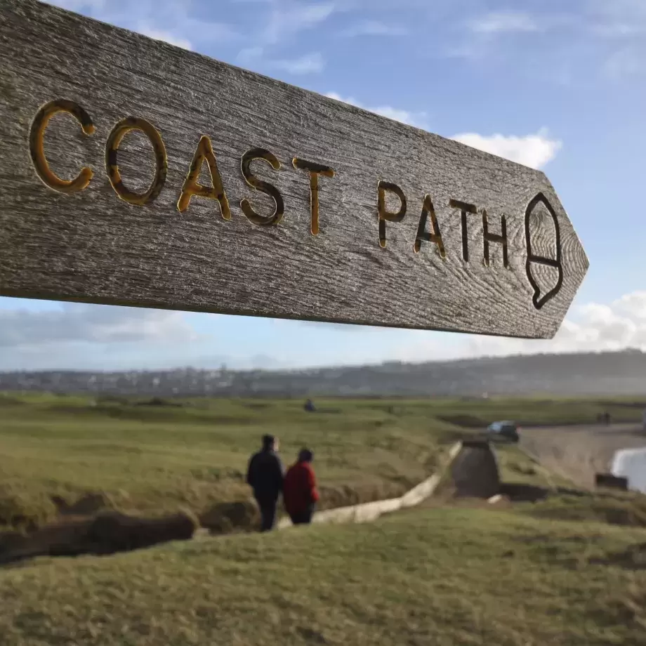 Close up of Southwest Coast Path sign with beach in background