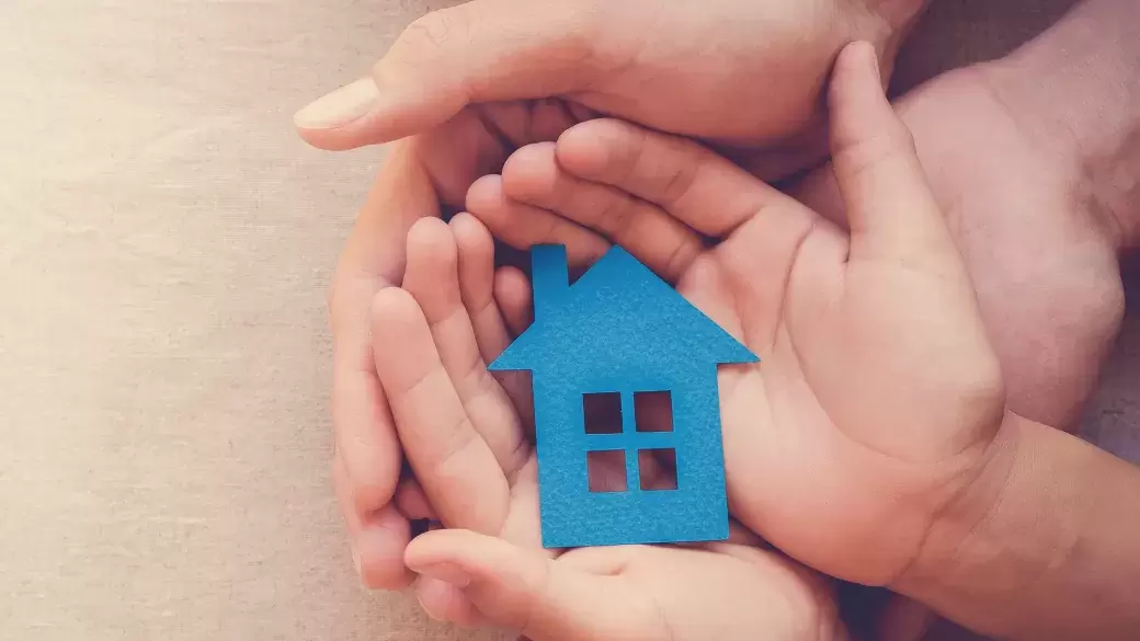 Paper cut out of a house being safely held in hands