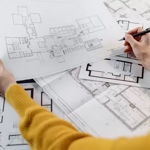 Plans being drawn up for a new housing development by female wearing a yellow jumper
