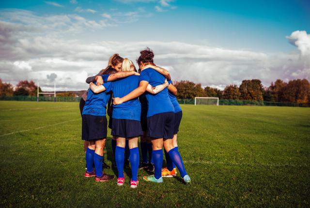Group of girls in a huddle on a football field