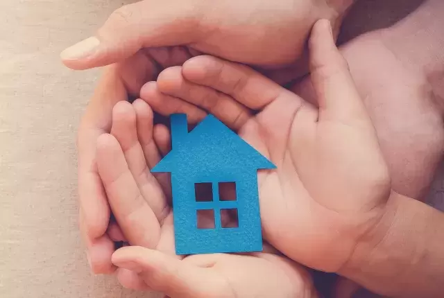 Paper cut out of a house being safely held in hands