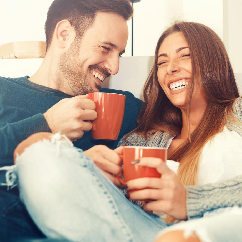 Happy couple drinking coffee together on sofa