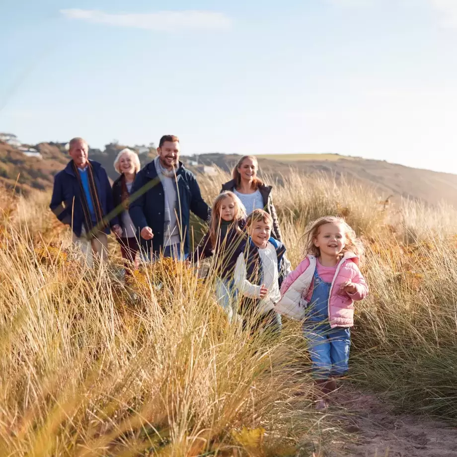 Family walking through sand dunes on North Devon beach on sunny day 